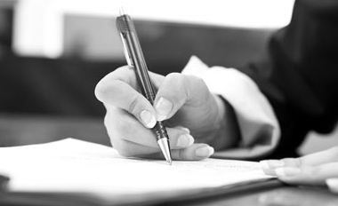 A hand signing a document with a fountain pen